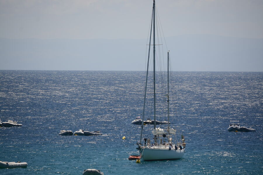 Sailboat at anchor among tenders in a quiet bay
